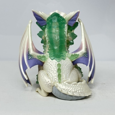 Boneco de dragão branco com detalhes verdes e asas roxas visto de costas