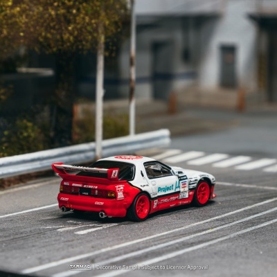 Miniatura de carro de slot branco e vermelho com rodas vermelhas em cenário urbano em miniatura.