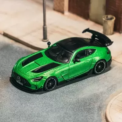 Miniatura de carro desportivo verde metálico com detalhes pretos numa rua simulada