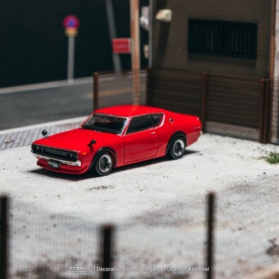 Miniatura de carro desportivo clássico vermelho num cenário urbano.