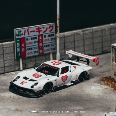 Miniatura de carro de corrida branco com decoração vermelha e preta junto a muro e sinalização em japonês