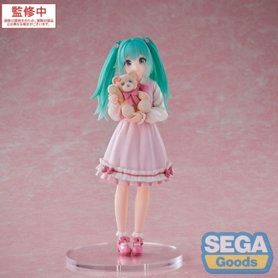 Figura colecionável de personagem feminina com cabelo verde-azulado e vestido rosa segurando ursinho de pelúcia
