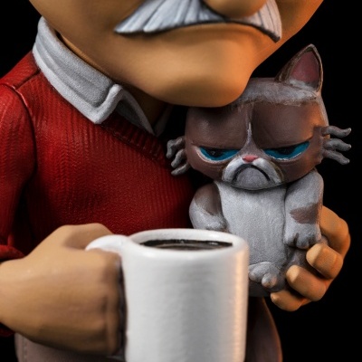 Boneco caricatural de homem segurando um gato cinza zangado e uma caneca branca com café