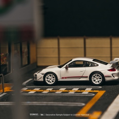 Miniatura de carro desportivo branco RS 4.0 numa cena de parque de estacionamento urbano.