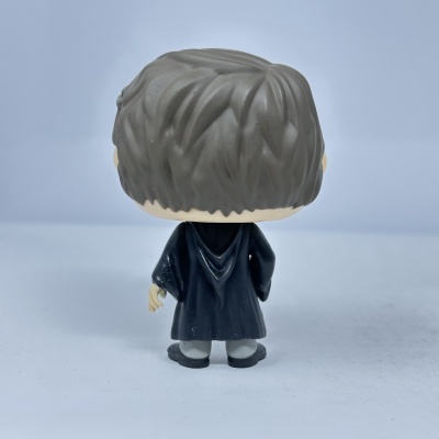 Boneco estilizado de costas com cabelo castanho escuro, roupa preta e calçado cinzento.