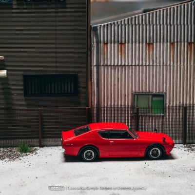Miniatura de carro desportivo vermelho em frente a edifício metálico cinzento