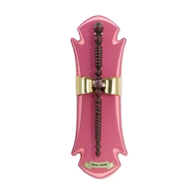 Varinha mágica de madeira escura montada em base decorativa rosa com detalhes dourados