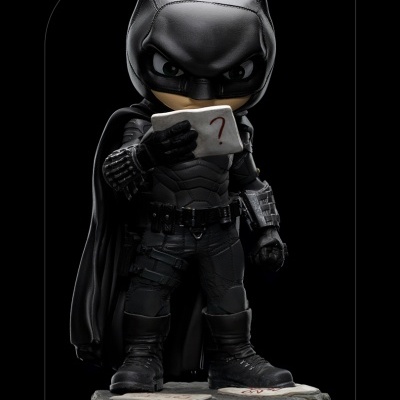 Figura colecionável do Batman em preto segurando cartão com ponto de interrogação