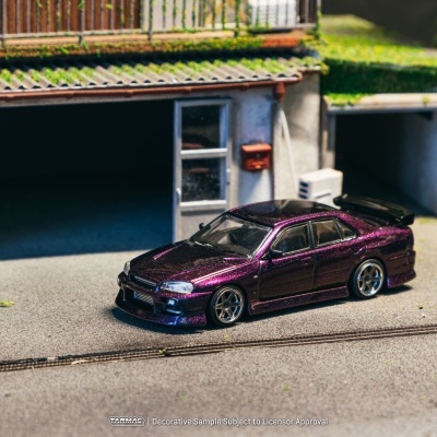 Miniatura de carro desportivo roxo metálico com spoiler diante de garagem