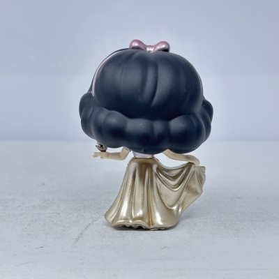 Boneco Funko Pop com cabelo preto grande e vestido dourado visto de trás