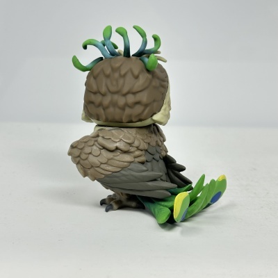 Figura decorativa de pássaro colorido com penas detalhadas e cauda verde com pontas amarelas e azuis