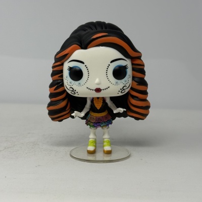 Figura colecionável de vinil com rosto calavera, cabelo preto e laranja, roupa colorida