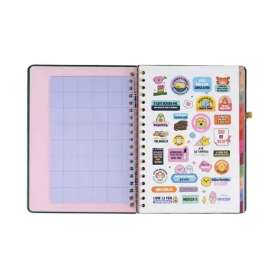 Caderno espiral aberto com autocolantes coloridos numa página e grid rosa na outra.