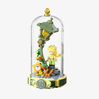 Escultura LEGO Le Petit Prince em campânula transparente com boneco e candeeiro verde.