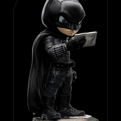 Estatueta colecionável de Batman em traje preto segurando um envelope com ponto de interrogação