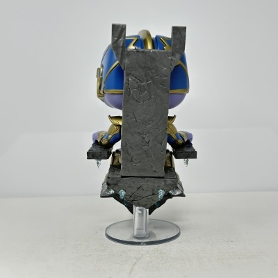 Figura Funko Pop em azul, dourado e roxo sentada num trono cinzento com suporte transparente