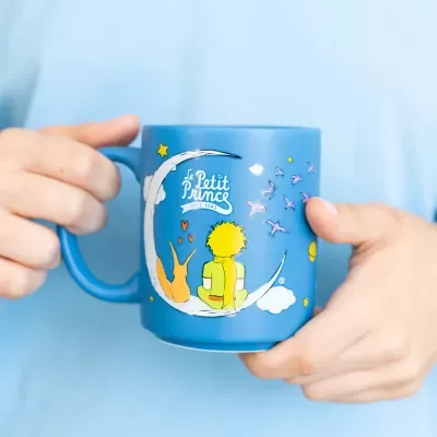 Caneca azul com desenho do Pequeno Príncipe e raposa na lua, com texto Le Petit Prince.