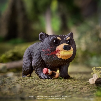 Figura colecionável de urso preto com manchas vermelhas e pedaço de madeira