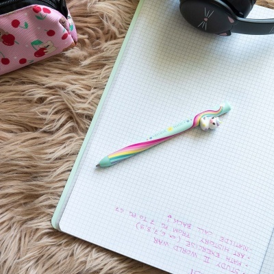 Caderno quadriculado, caneta unicórnio colorida, estojo rosa com cerejas e headphones pretos com desenho de gato