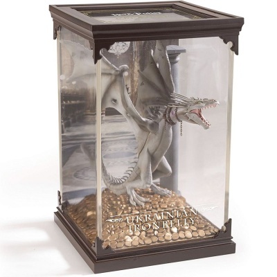 Figura de dragão cinzento numa caixa de vidro com moedas douradas e texto 'UKRAINIAN IRONBELLY'