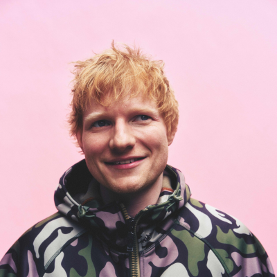 Homem com casaco camuflado com capuz e cabelo ruivo, fundo rosa