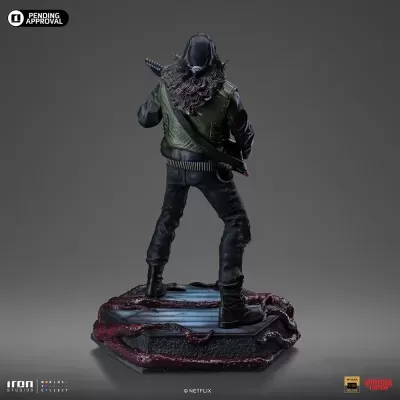 Figurino colecionável de personagem com colete verde e base hexagonal preta com detalhes vermelhos.