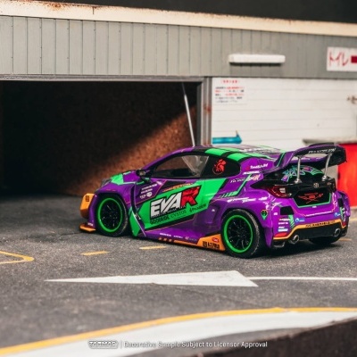 Miniatura de carro desportivo roxo e verde com rodas verdes junto a garagem.