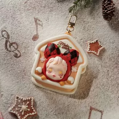 Chaveiro em forma de casa de gengibre com rosto decorativo e laço xadrez, em fundo com padrões musicais e biscoitos star