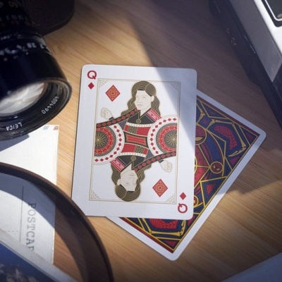 Cartas de baralho com ás e dama de ouros sobre mesa de madeira.