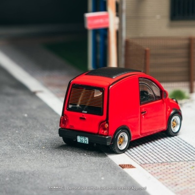 Miniatura de carro vermelho encostado a passeio pavimentado.