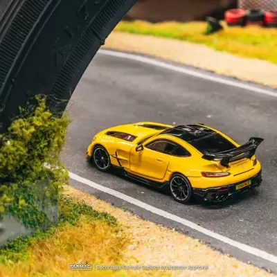 Carro de brinquedo amarelo com asa preta numa estrada de miniatura