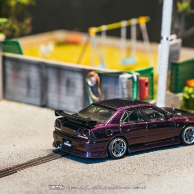 Modelo de carro roxo metálico brilhante com rodas prateadas e parque infantil ao fundo
