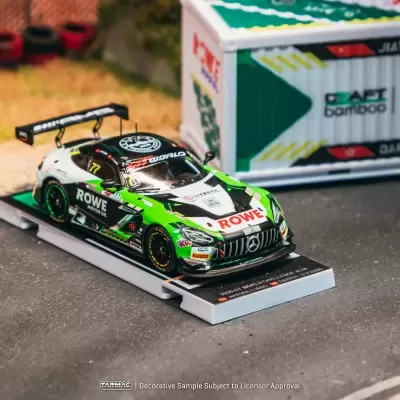 Miniatura de carro de corrida verde, branco e preto numa pista com pneus vermelhos e pretos ao fundo