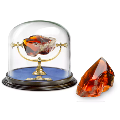 Mineral âmbar castanho alaranjado exposto em cúpula de vidro com base de madeira e suporte dourado