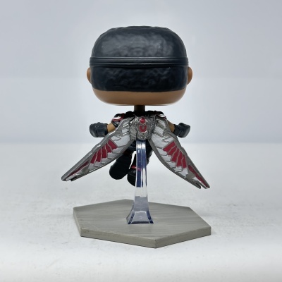 Boneco estilizado Funko Pop com asas metálicas prateadas e detalhes vermelhos em base cinza.