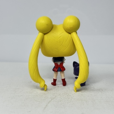 Figura de brinquedo com cabelo amarelo e uniforme azul vista de costas