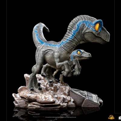Figura de velociraptor cinzento com risca azul e base rochosa com logo Jurassic Park