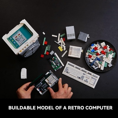 Modelo de computador retro construído com blocos tipo LEGO sobre mesa preta com várias peças e teclados