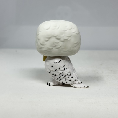 Figura colecionável de coruja branca com detalhes em preto vista de trás