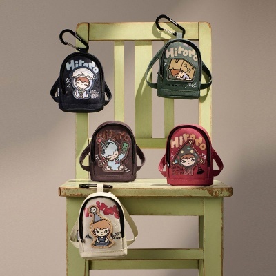 Cinco mochilas pequenas com desenhos de personagens penduradas e apoiadas numa cadeira verde desgastada.