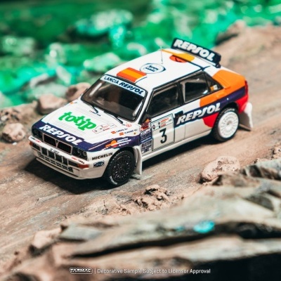 Miniatura de carro de rali Lancia branco com logos REPSOL e totip em estrada de terra