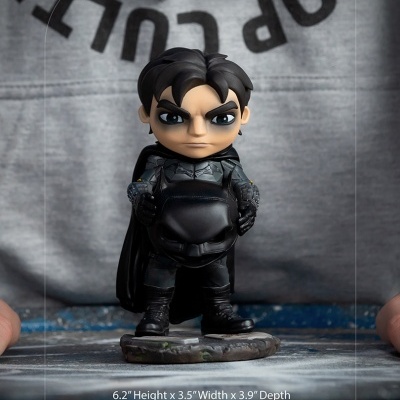 Figura colecionável preta com capa sobre base texturizada, dimensões e peso indicados