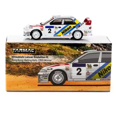 Miniatura Mitsubishi Lancer Evolution III branco com detalhes azuis e amarelos sobre caixa de produto.