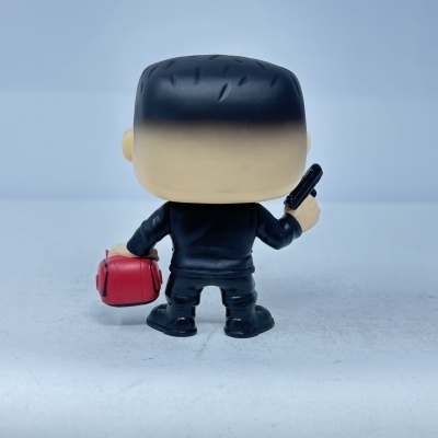 Figura Funko Pop de costas com fato preto, mala vermelha e pistola preta.