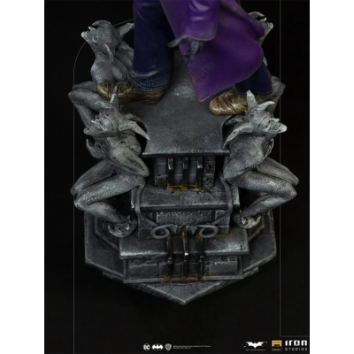 Estátua detalhada com figuras demoníacas e personagem com casaco roxo