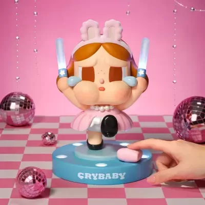 Figura colecionável pink com faixas de coelho e bastões luminosos sobre base azul com texto CRYBABY