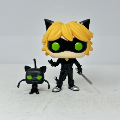 Figura Funko Pop com máscara preta e cabelo amarelo, e figura pequena preta ao lado