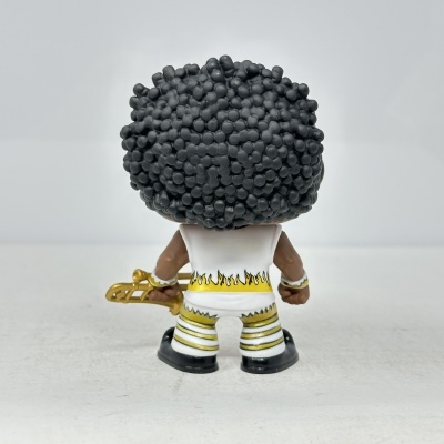 Brinquedo com cabelo preto volumoso, roupa branca com amarelo e preto, segurando trompete dourado