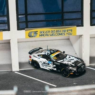 Miniatura de carro de corrida preto e branco numa pista em miniatura com placas amarelas acima