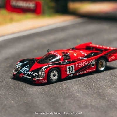 Miniatura de carro de corrida vermelho e preto com texto KENWOOD e número 10 numa pista modelada